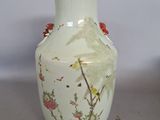 un vase blanc avec des fleurs et des oiseaux peints dessus