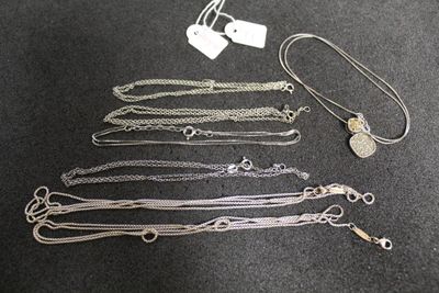 de nombreux colliers en argent sur un fond noir