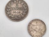 two silver coins sitting next to each other on a white surface