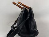 black leather bucket bag with bamboo handles on a white background