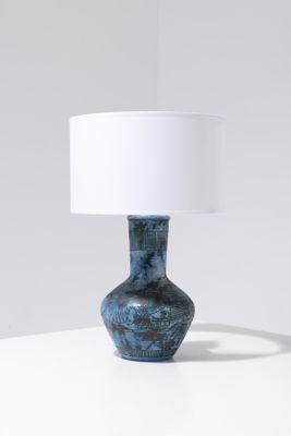 La lampe de table est bleue et est équipée d'un abat-jour blanc.