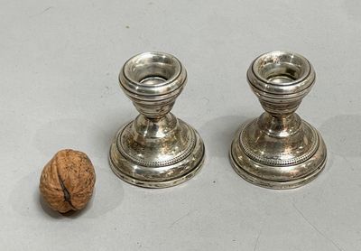 two silver candlesticks sitting next to a walnut