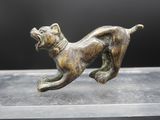 une statue en bronze représentant un chien courant sur une surface lisse