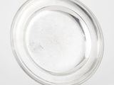 une assiette en argent posée sur un support, sur fond blanc