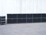 une commode noire avec des tiroirs, avec un mur blanc en arrière-plan
