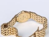 a gold watch on a gold bracelet on a white surface