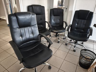 four black office chairs in a room with tile flooring