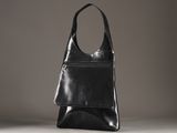 un sac en cuir noir posé sur une table blanche