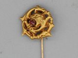 a gold brooch with a red stone in the center