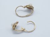 a pair of gold earrings with pearls on them on a white surface
