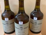 three bottles of wine sit on a wooden shelf in front of a wall