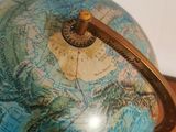 a blue globe with a gold handle on a wooden table