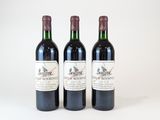 trois bouteilles de vin posées les unes à côté des autres sur une surface blanche