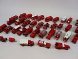 beaucoup de petits camions rouges en plastique posés sur une table blanche