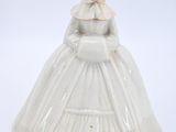 porcelain figurine of a woman in a white dress and bonnet