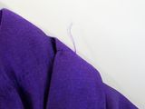 someone is sewing a purple shirt on a white surface