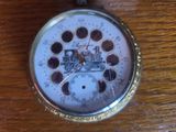 a silver pocket watch with a clock on it on a wooden table
