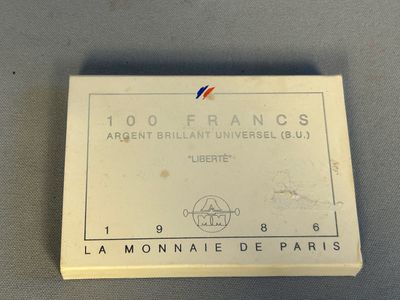 une image représentant une boîte blanche sur laquelle figure une étiquette rouge, blanche et bleue