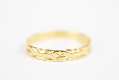 a close up of a yellow gold wedding ring on a white background
