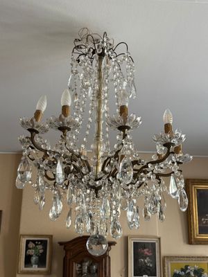 un lustre au milieu d'une pièce dont les murs sont ornés de tableaux
