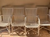 three white wicker chairs sitting on a patio next to a wall