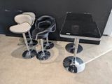 trois tabourets de bar noirs et blancs et une table dans une pièce