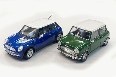 two miniature cars sitting side by side on a white surface