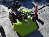 a small green machine sitting on the ground next to a lawn mower