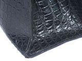 black crocodile skin handbag on a white background with a black handle