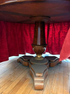 une photo d'une table en bois avec un rideau rouge en arrière-plan