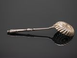 an antique silver spoon with a leaf shaped handle on a black surface
