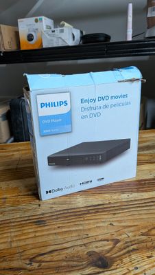 emballage d'un lecteur DVD posé sur une table en bois dans une pièce