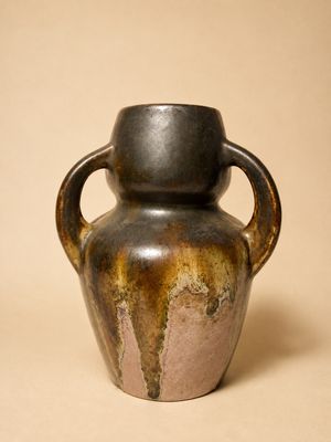un vase marron muni d'une anse, sur fond beige