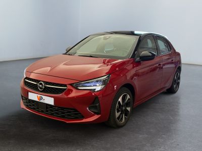La voiture rouge est garée dans une grande pièce au sol noir.