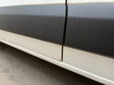 the side of a white car with a black stripe on the side