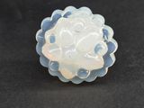 a close up of a white and blue flower broochle on a black surface