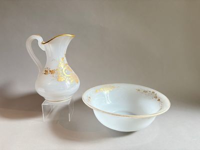 un bol blanc et un pichet blanc et doré posés sur une table