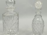 deux bouteilles en verre transparent posées l'une à côté de l'autre sur une surface blanche