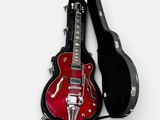 a red electric guitar in a black case on a white surface