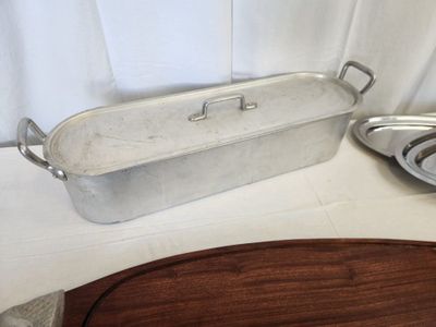 a large metal pan sitting on a table next to a wooden cutting board
