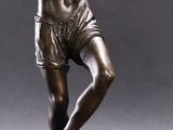 a bronze statue of a man holding a tennis racquet