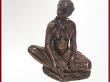 une statue en bronze représentant une femme assise sur un coussin