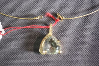 a necklace with a green stone on a red string