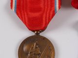 two medals are placed on a white surface with a red ribbon around them