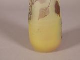 a yellow vase with leaves on it sitting on a table