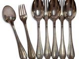 six spoons and a fork are lined up on a white surface