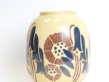 a yellow vase with blue flowers on it on a white surface