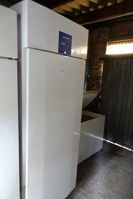 two white refrigerators in a room with a brick wall