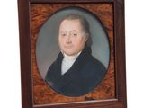 portrait d'un homme vêtu d'un manteau noir et d'une chemise blanche, dans un cadre en bois