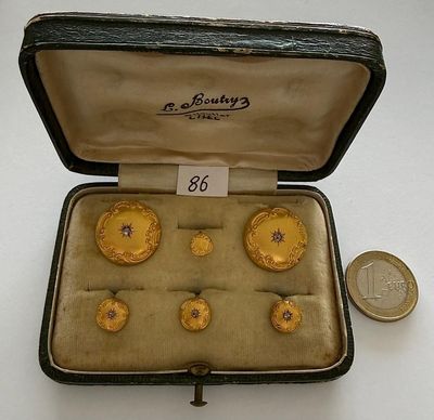 a box with six gold rings in it and a coin next to it